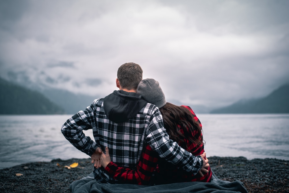 A young couple snuggles on the rocky shores of Bandon Beach in Oregon.