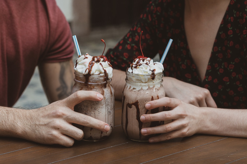 Couple enjoying chocolate shakes. Visit Clinton's Soda Fountain on your secluded romantic getaways in Missouri.