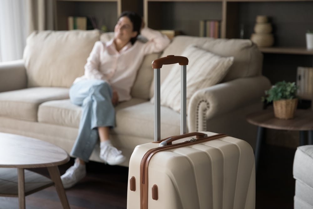 Suitcase with woman sitting on a couch in the background - representing boutique lodging and places to stay in Milwaukee
