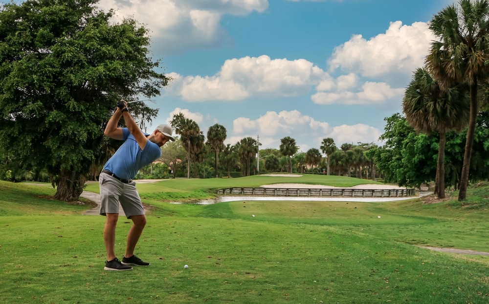 A golfer teeing off on a beautiful golf course, one of the best things to do in Palm Coast, FL.