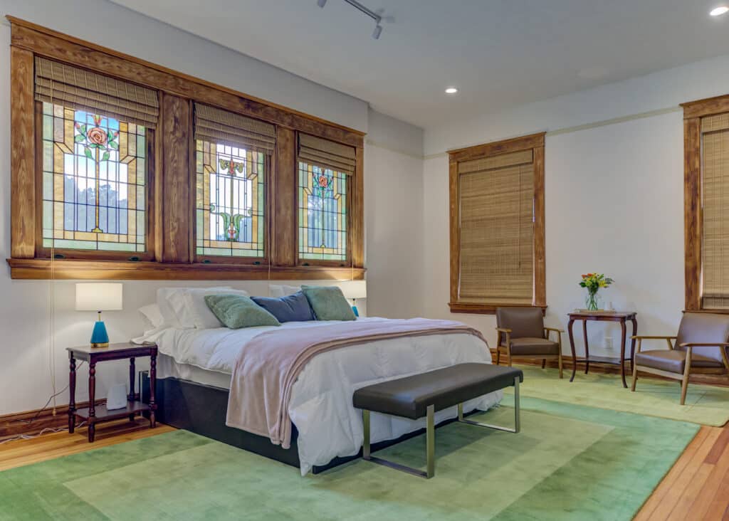 The Louis Suite bed and stained glass windows at Oak Hall, one of the best boutique hotels in Vicksburg.