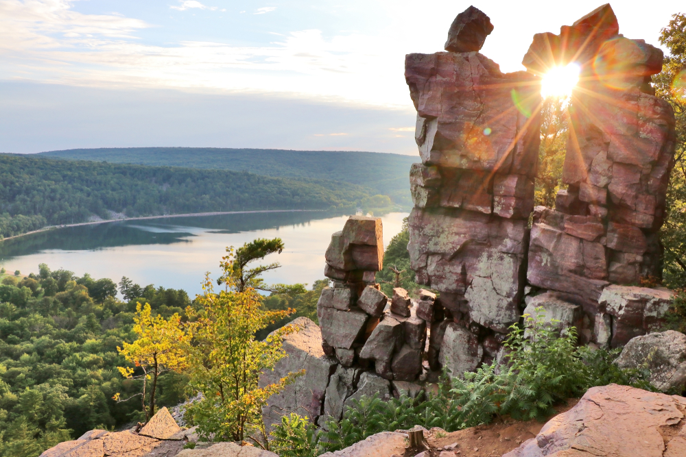 View of the south shore of Devil's Lake with the sun shining throught the Devil's Doorway rock formation in Devil's Lake State Park, one of the best state parks in Wisconsin.
