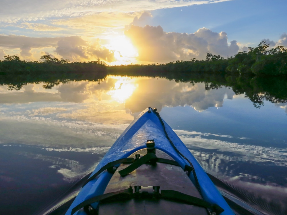 Take a paddle along the Intracoastal Waterway in Florida. Blue kayak in foreground as the sun rises.