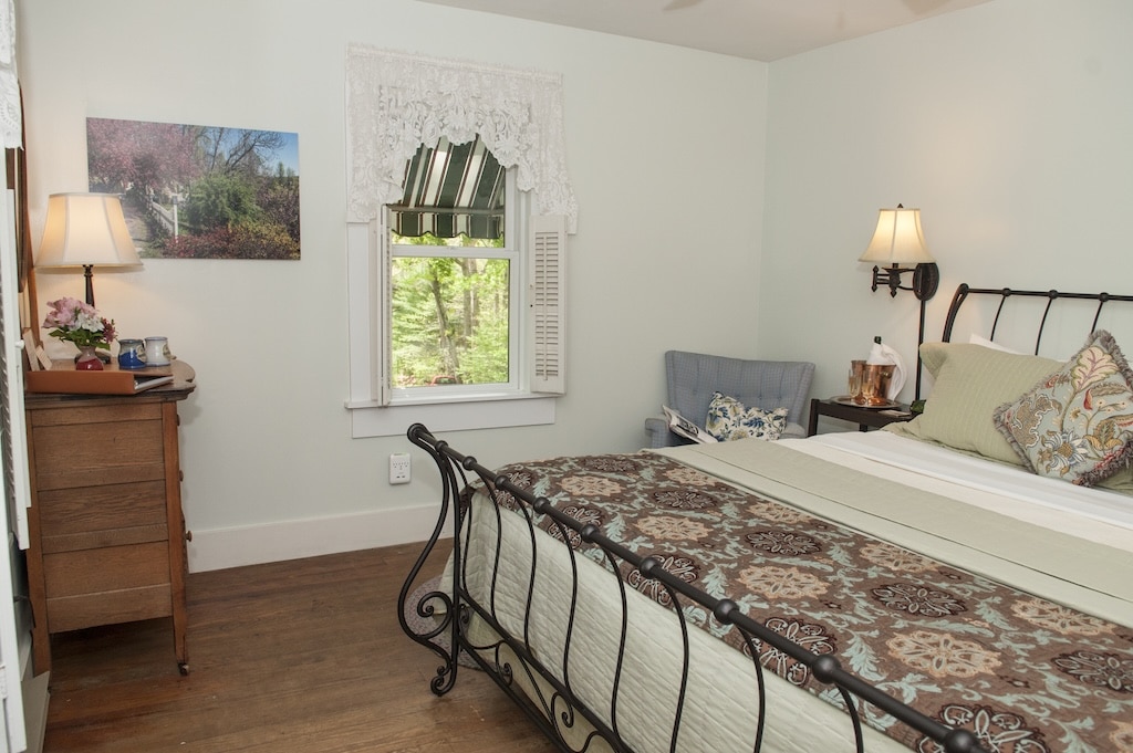 Enjoy Staying in the New Room 2 at one of the best Saluda Hotels this fall. Image of iron bed and window.