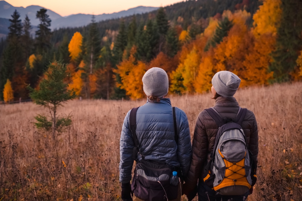 Visit Black Rock Mountain State Park, a romantic escape. Image of two hikers' backs looking out at fall foliage.