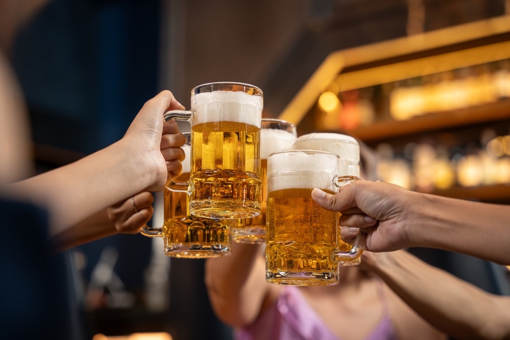 Visit the Helen Georgia Oktoberfest this fall. Image of five mugs of beers coming together to cheers.