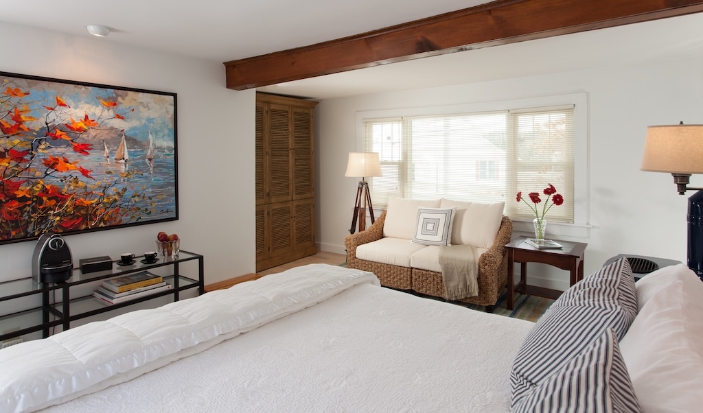 Stay at the best New Hampshire Bed and Breakfast, during one of your New Hampshire getaways for couples. White bed with couch and lamp.