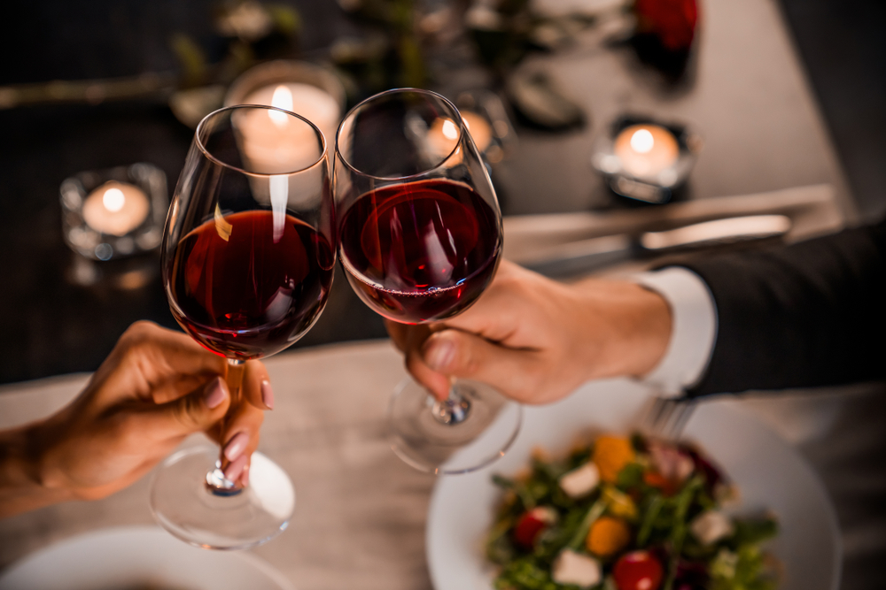 Couple toasting red wine on a date night on romantic Wisconsin getaways.