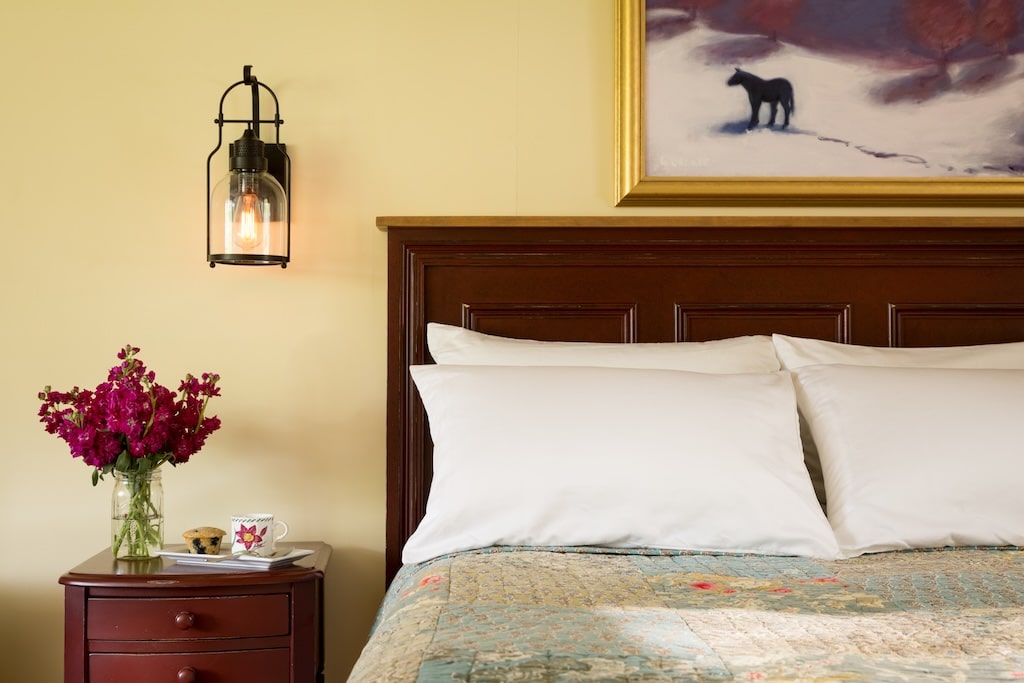 Stay at the best White Mountains Bed and Breakfast this winter! Enjoy this queen bed with beautiful flowers on the nightstand.