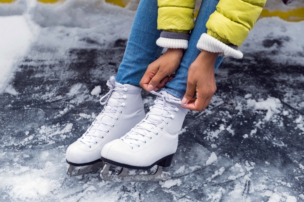 Young woman putting ice skates on at outdoor rink near Cayuga Nature Center.