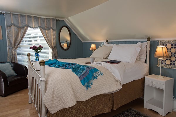 Bedroom with white side tables and a bed with white quilt at our Friday Harbor lodging