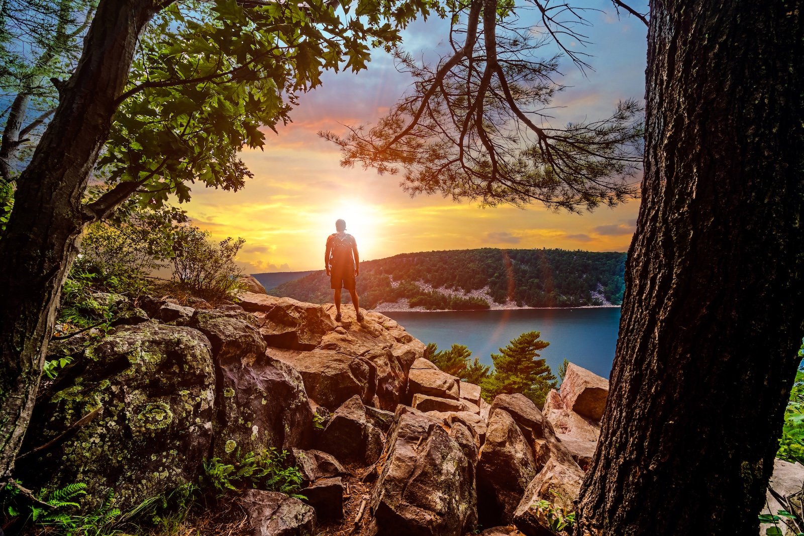 The best Devil's Lake Trails to explore on your next visit to this stunning Wisconsin State Park. A man on a trail looking out over the lake