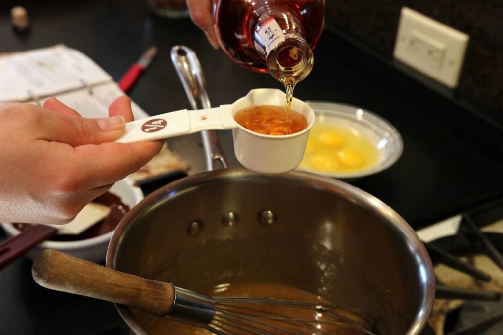 hand measuring 1/4 cup of liquid into a bowl