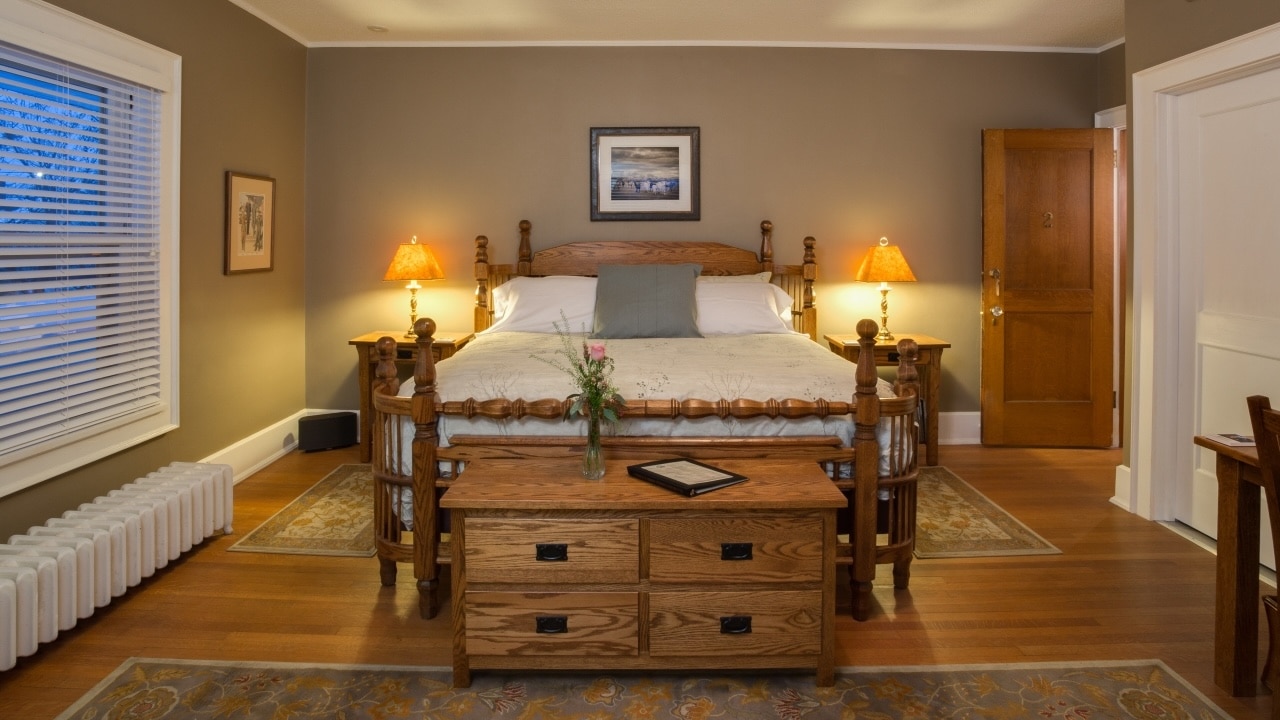 Stay at one of the most unique hotels in Wausau WI and enjoy a cozy room like this one with a kind bed and antique furnishings.