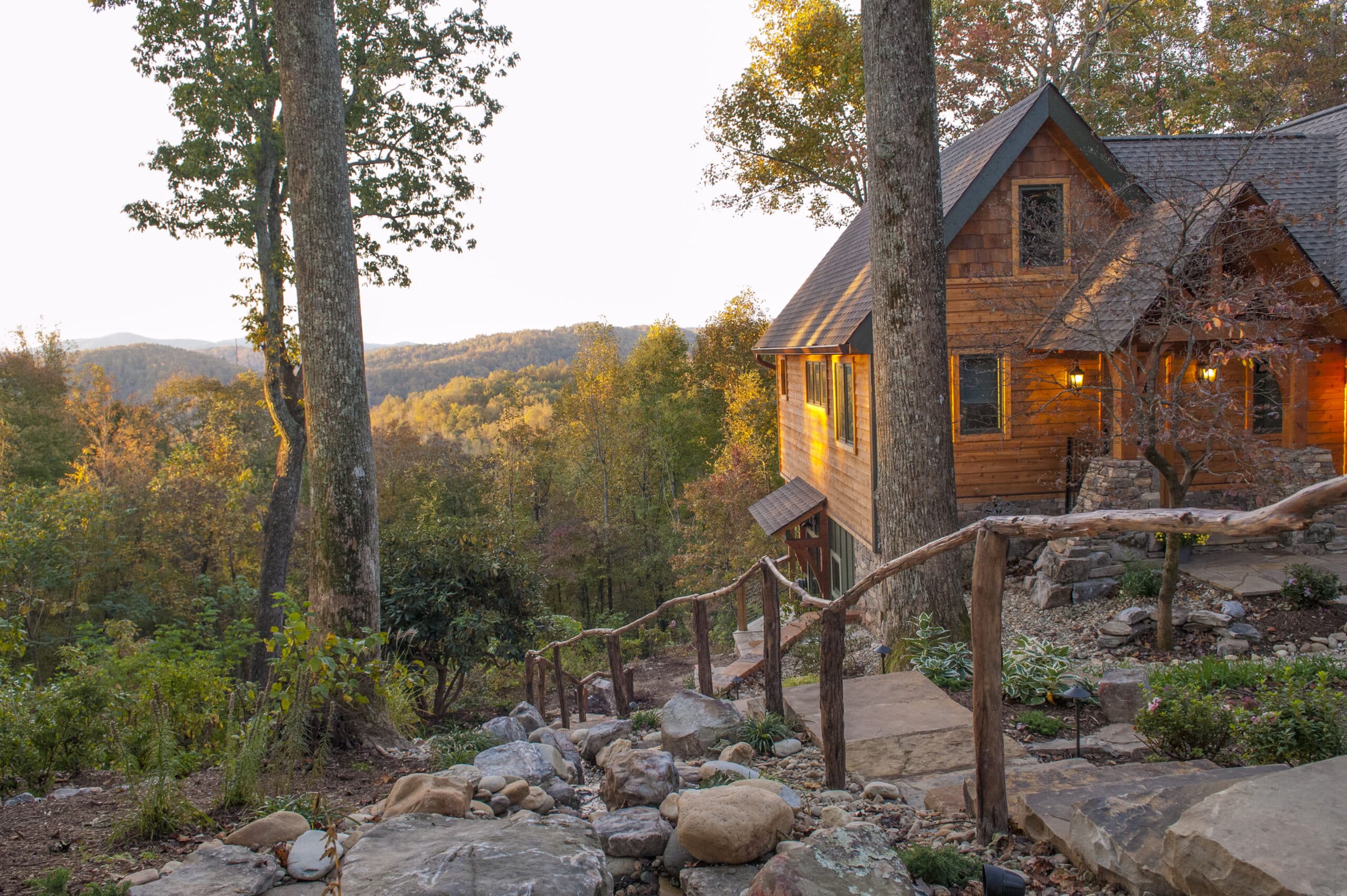 At this Bed and Breakfast in the NC mountains, you can see a beautiful view of a cabin surrounded by mountains and a waterfall.