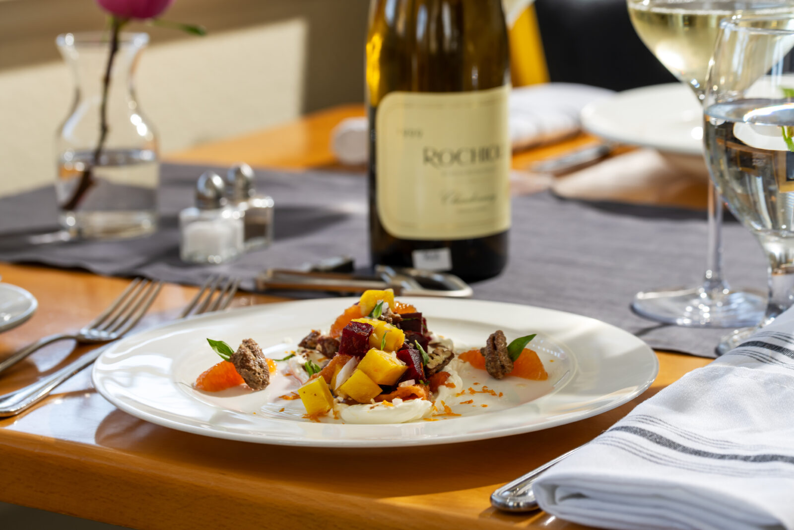 Table set at Restaurant 301 with a beet salad and bottle of wine from our impressive collection.