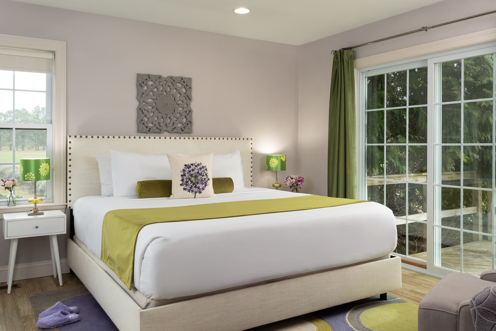 A guest room at the best Bed and Breakfast in Maryland, complete with a plush bed by a window, with lavender walls and and a green throw blanket.