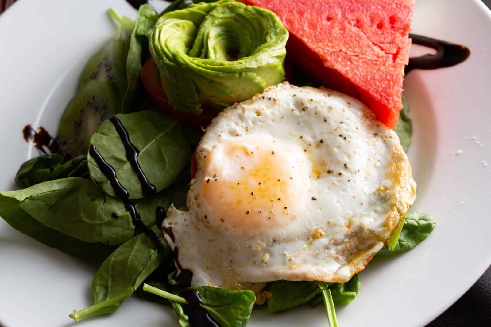 Enjoy a gourmet breakfast at our Deep Creek Lake hotel: greens, avocado flower, sunny-side up egg, watermelon. 