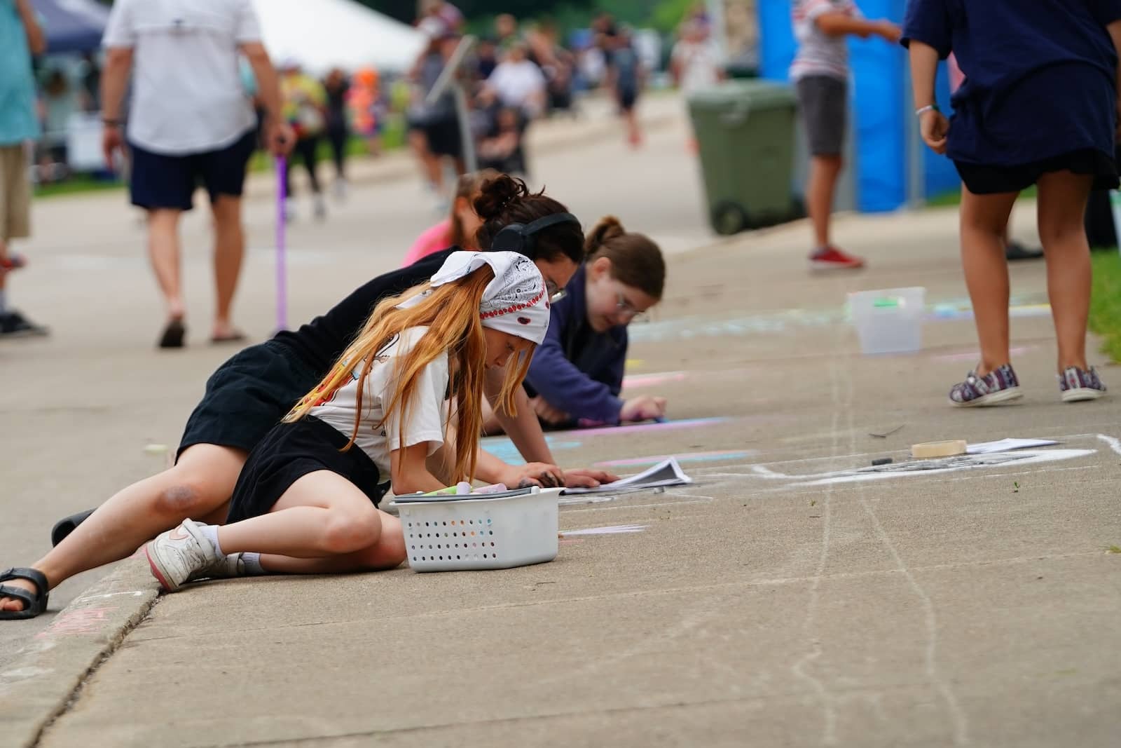 Girls working on a chalk drawing on the sidewalk at Chalkfest, one of the popular Wausau events.