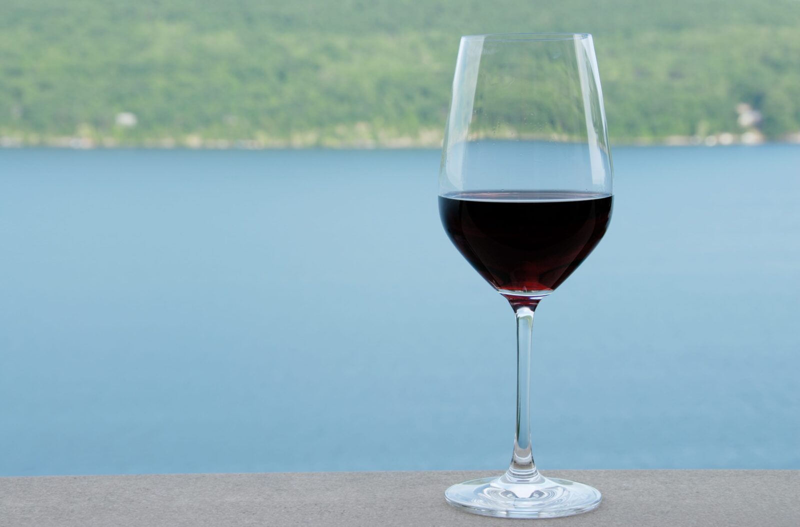 A glass of wine with a view of Seneca Lake at Fox Run Vineyards.