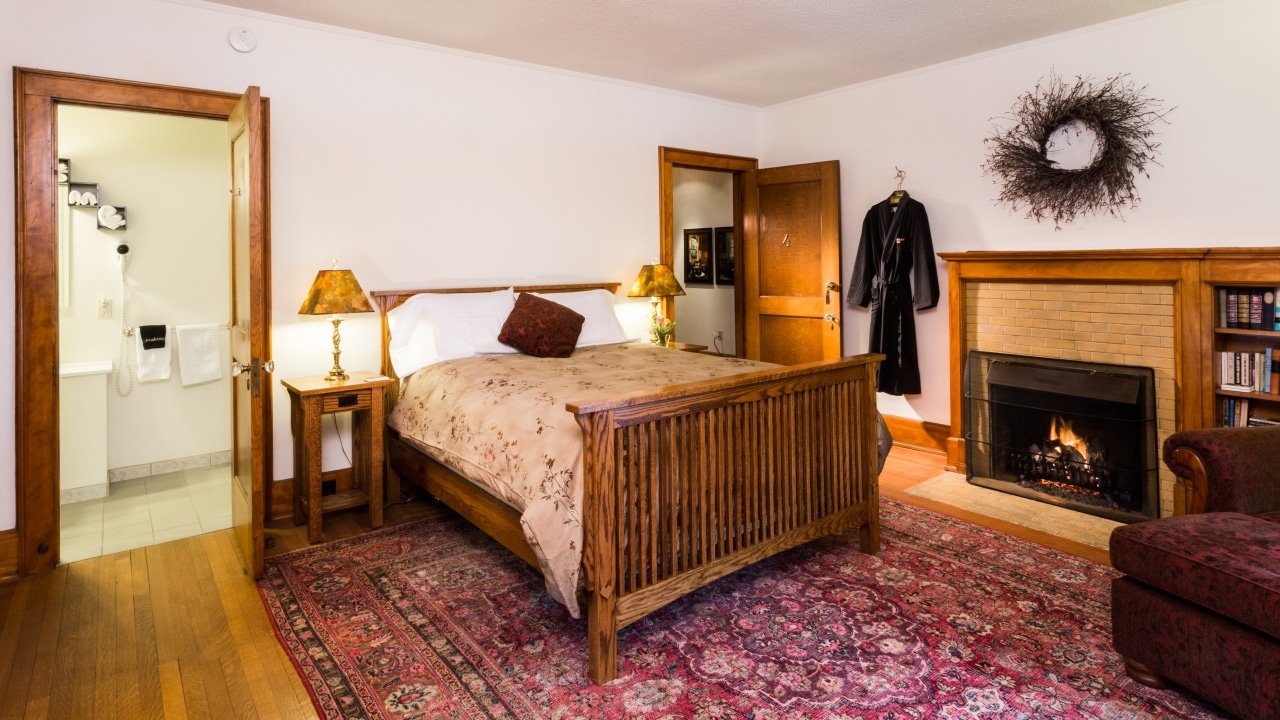 A bed beside a fireplaces with a robe hanging in a guest room at one of the best hotels in Wausau Wi.