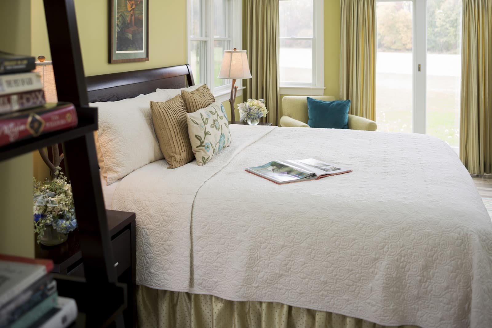 A comfortable bed with throw pillows next to windows in a room with natural light at a bed and breakfast in Maryland.