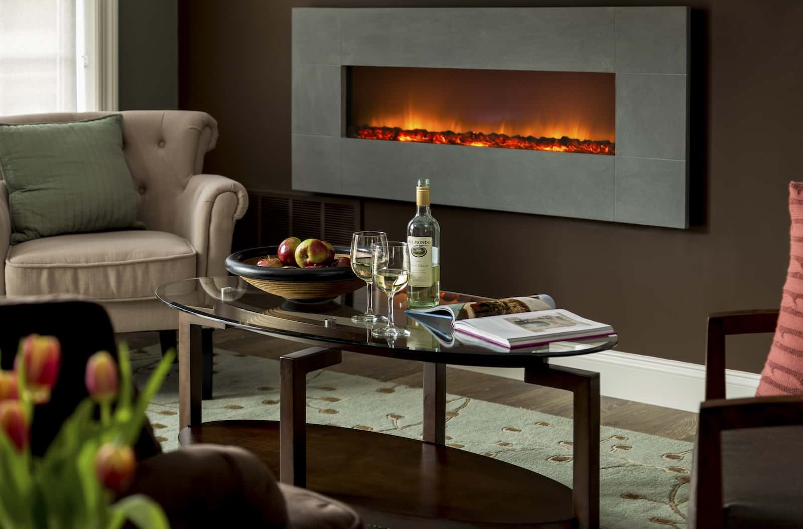 A fireplace by a coffee table with wine at a cozy Maryland Bed and Breakfast.