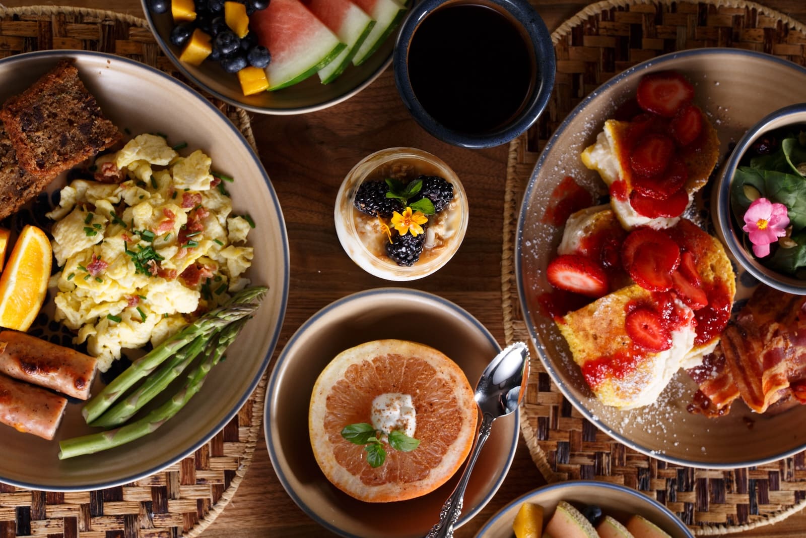 At the best Bed and Breakfast Wisconsin, you'll find a spread of breakfast on a wood table featuring a yogurt parfait, eggs, french toast, and a grapefruit.