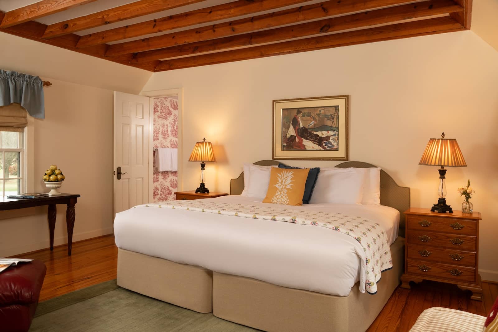 A king size bed with artwork above and two nightstands with lamps beside it in a room at the best bed and breakfast in Maryland.