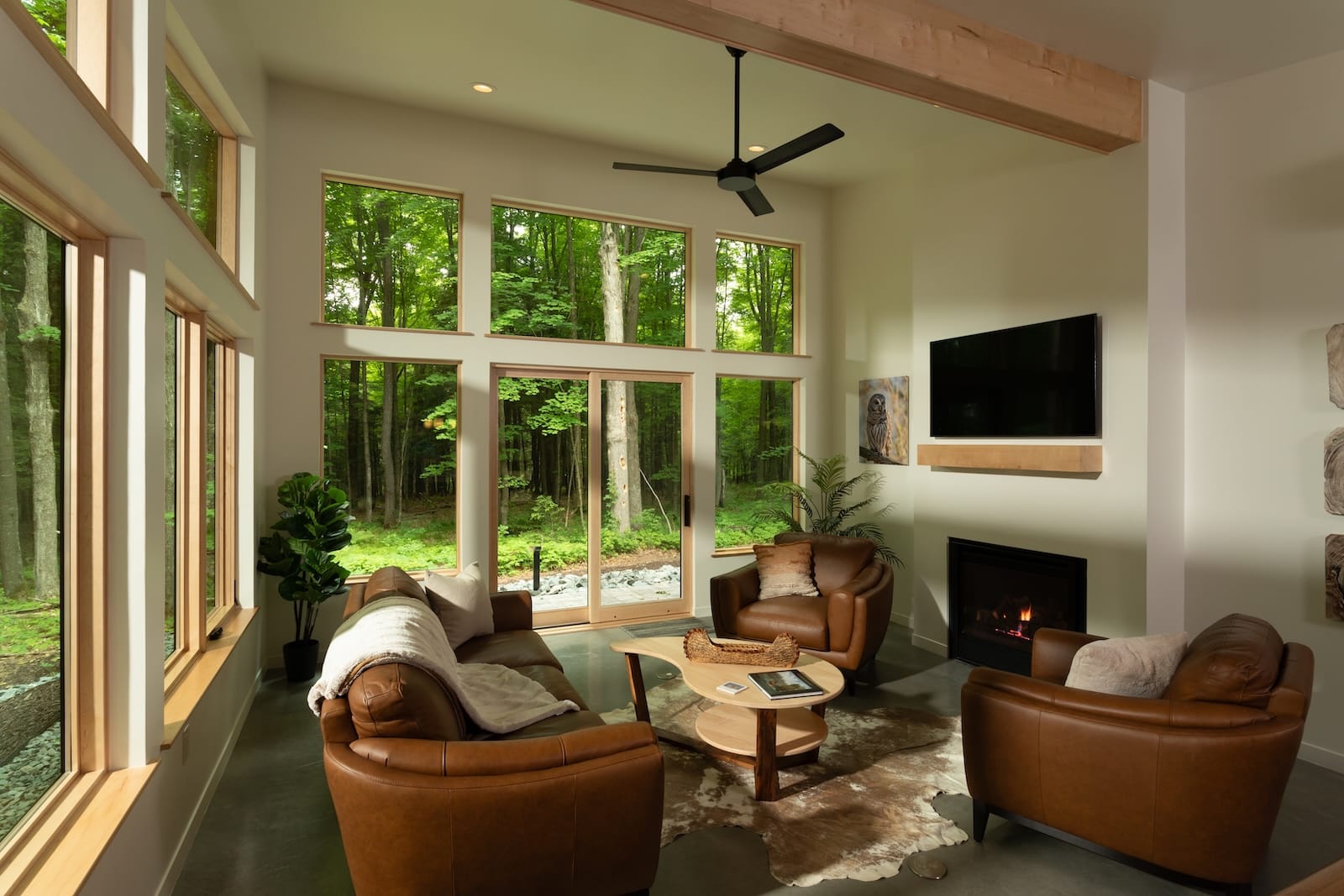 The living room of one of the best cabins in Wisconsin, featuring comfortable chairs, open windows, a fireplace, and a television.