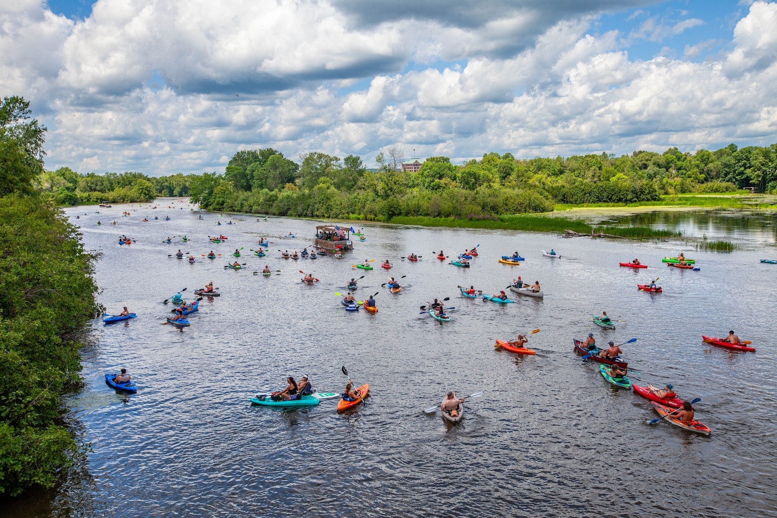 A river with trees on either side and people enjoying Wisconsin River kayaking.