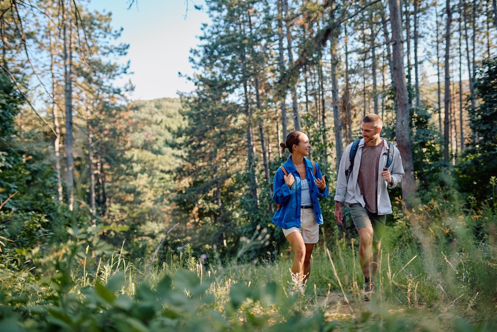 Couple of hikers with backpacks walking in a forest path and talking, enjoying a summer vacation day in the nature in the Mad River Valley Vermont