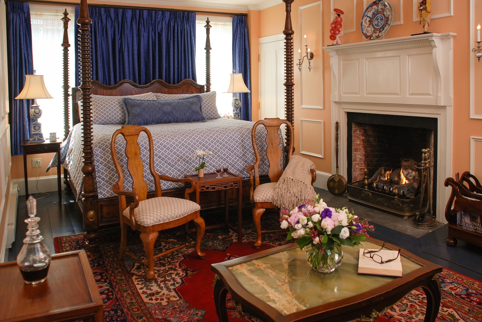 A bed by a fireplace with a seating area in front, what you'll find at one of the best Exeter hotels. 
