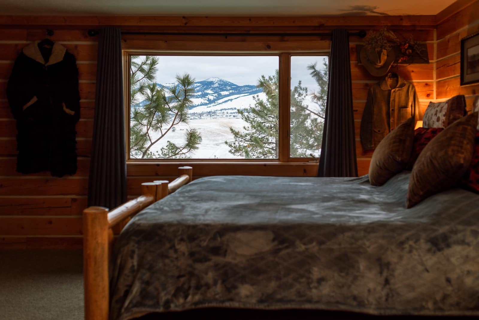 A guest room at one of the best places to stay in Missoula Montana, with a bed by a window with snowy mountains in the background. 