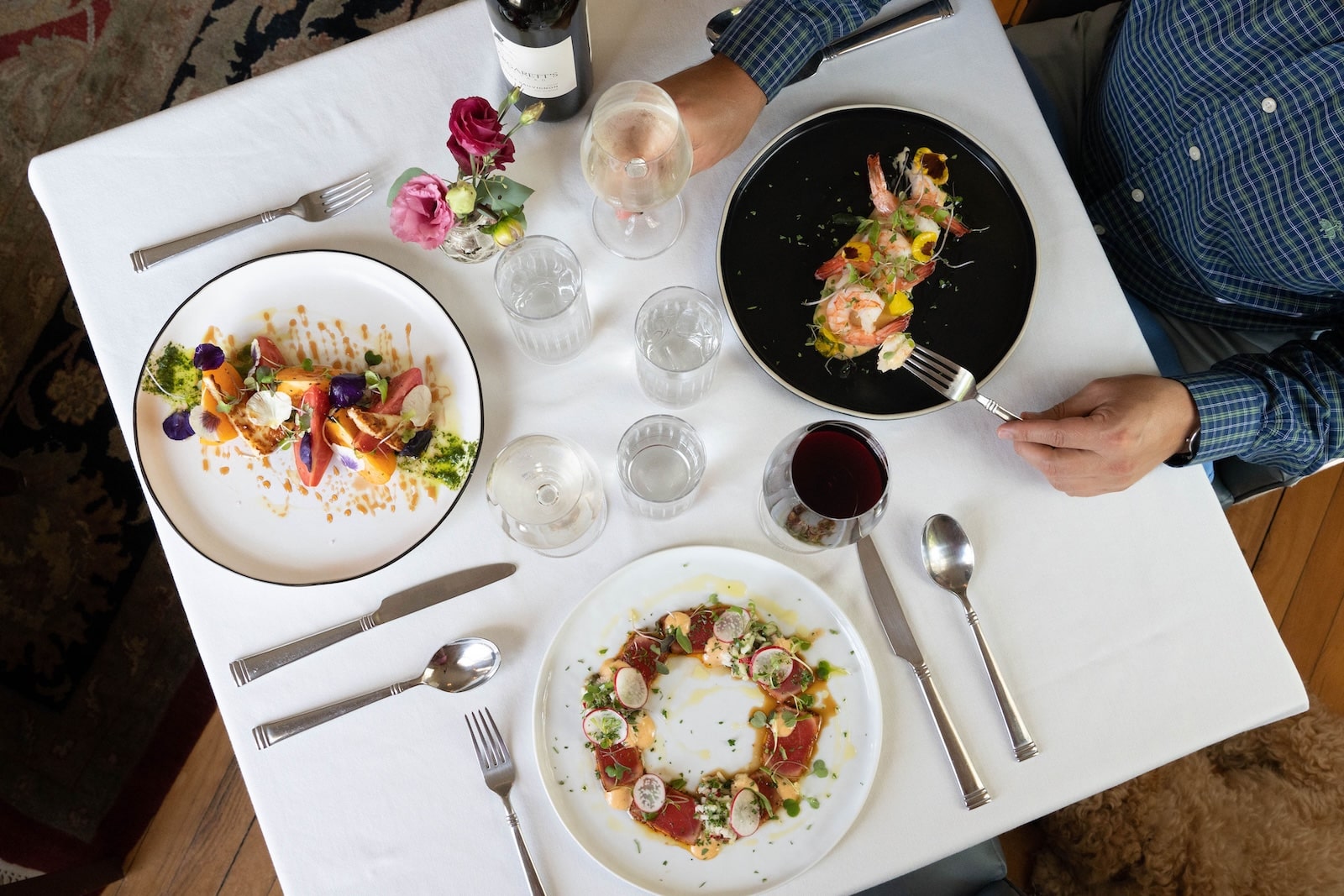 A table scape of three fine-dining dinner plates with silverware, and wine, at one of the best Exeter NH restaurants.