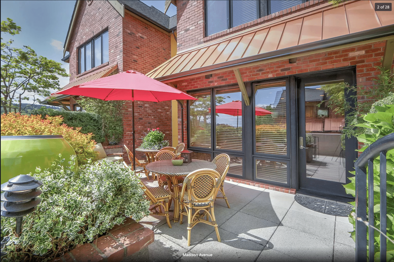 Fall is mild enough to enjoy our courtyard patio at our Bainbridge Island Boutique Hotel. Seating area with a red sun umbrella.