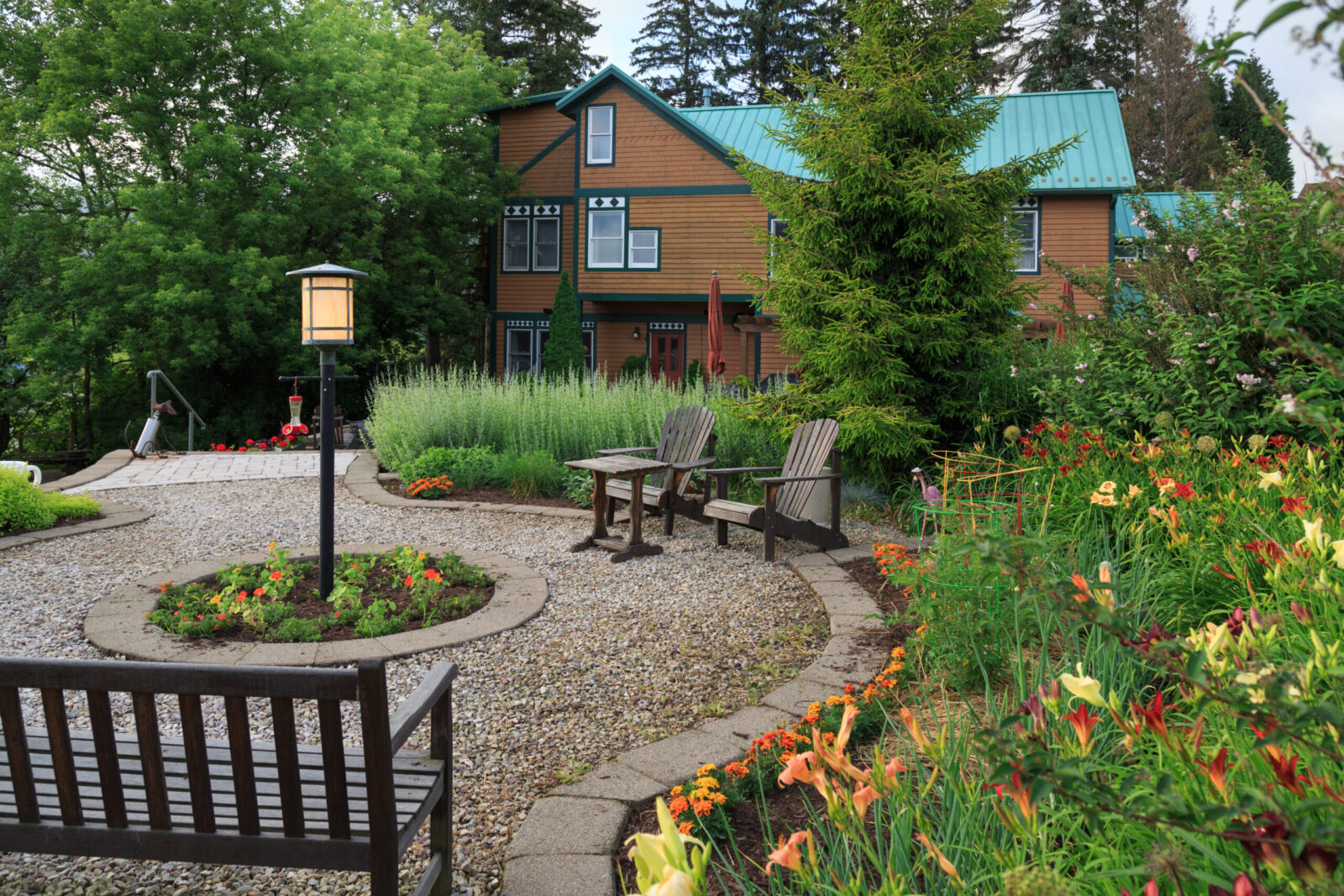 Gardens at our Deep Creek Lake Hotel with brown mansion with green roof in background.