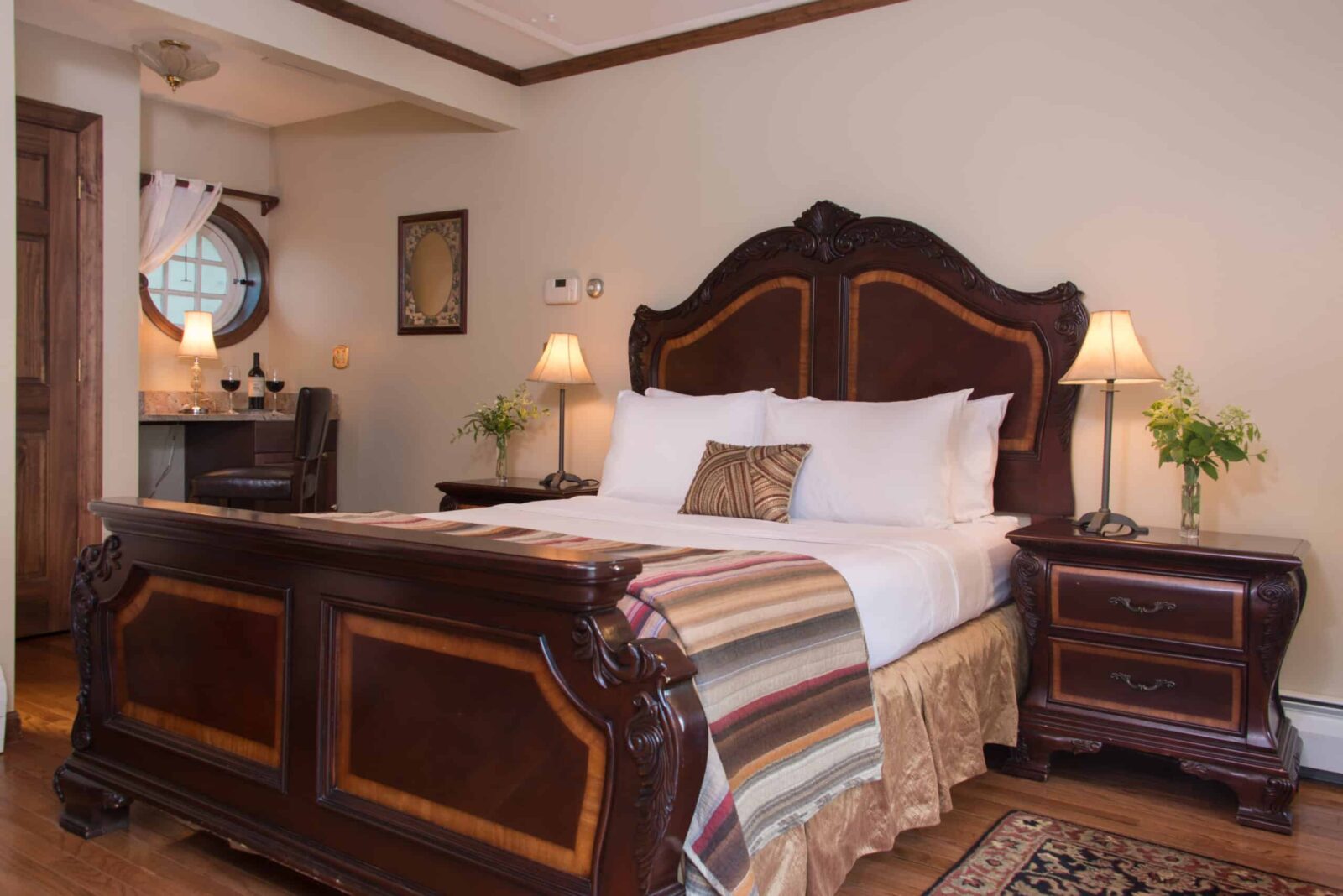 the Maple Room bed, with nightstands, lamps, flowers and striped bedding in fall colors at our Bed and Breakfast in Brattleboro.