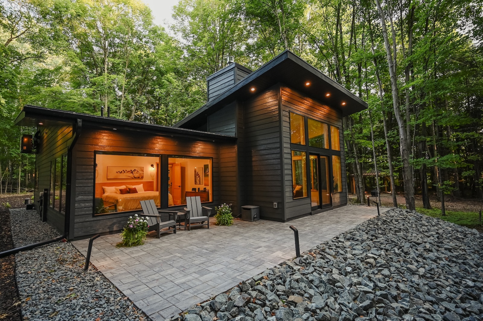 A modern cabin in the woods with a patio, seating area, and large windows with warm light, one of the best luxury cabins in Wisconsin.