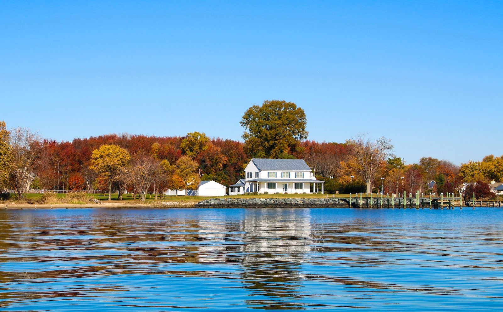 Experiencing the fall foliage on the Chesapeake Bay, like this white house surrounded by fall leaves on the trees, is one of the many things to do in Rock Hall MD in the fall.