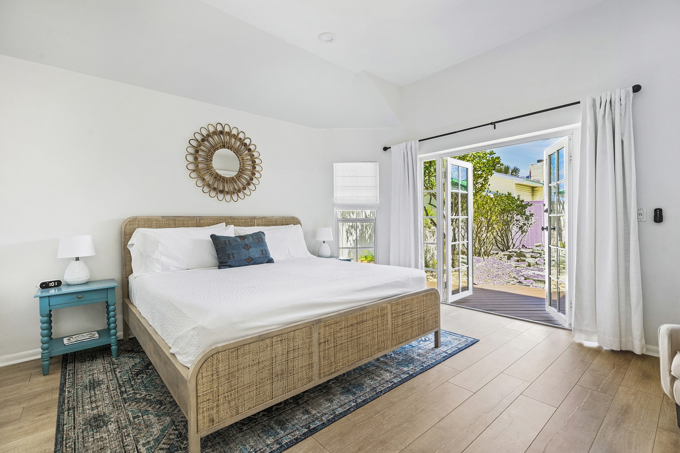Guest room bed at our Flager Beach Hotel. White walls, coastal beach style furnishings with white linens.