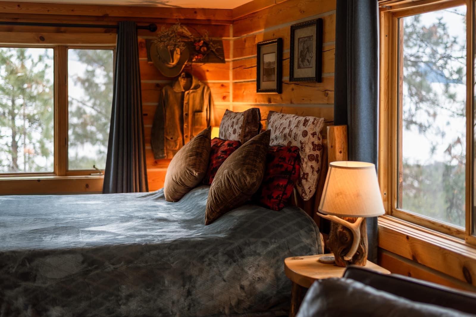 A bed by two windows, a lamp, in a cabin-like setting at a Montana Bed and Breakfast.