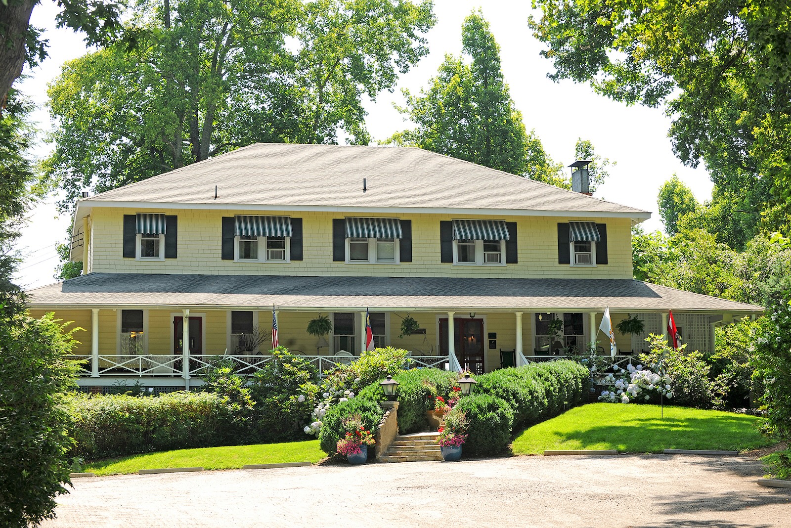 A yellow two-story building framed by trees, showcasing the best bed and breakfast NC mountains.