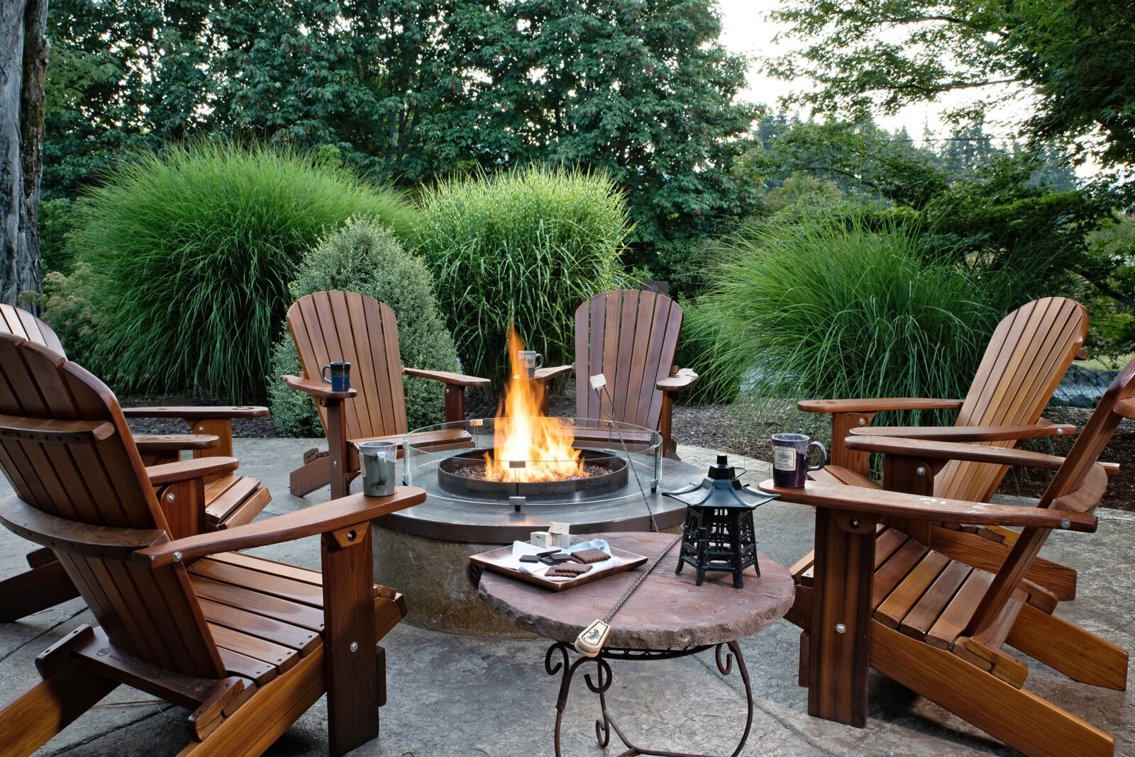 Relax by the fire pit at Carson Ridge Cabins, wood adirondack chairs around a fire pit with smores makings.