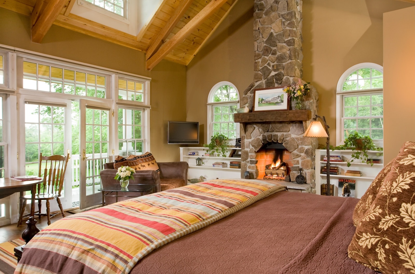 The Dream Cottage featuring a fireplace, wooden beams, and a large bed at a Bed and Breakfast in New Hampshire.