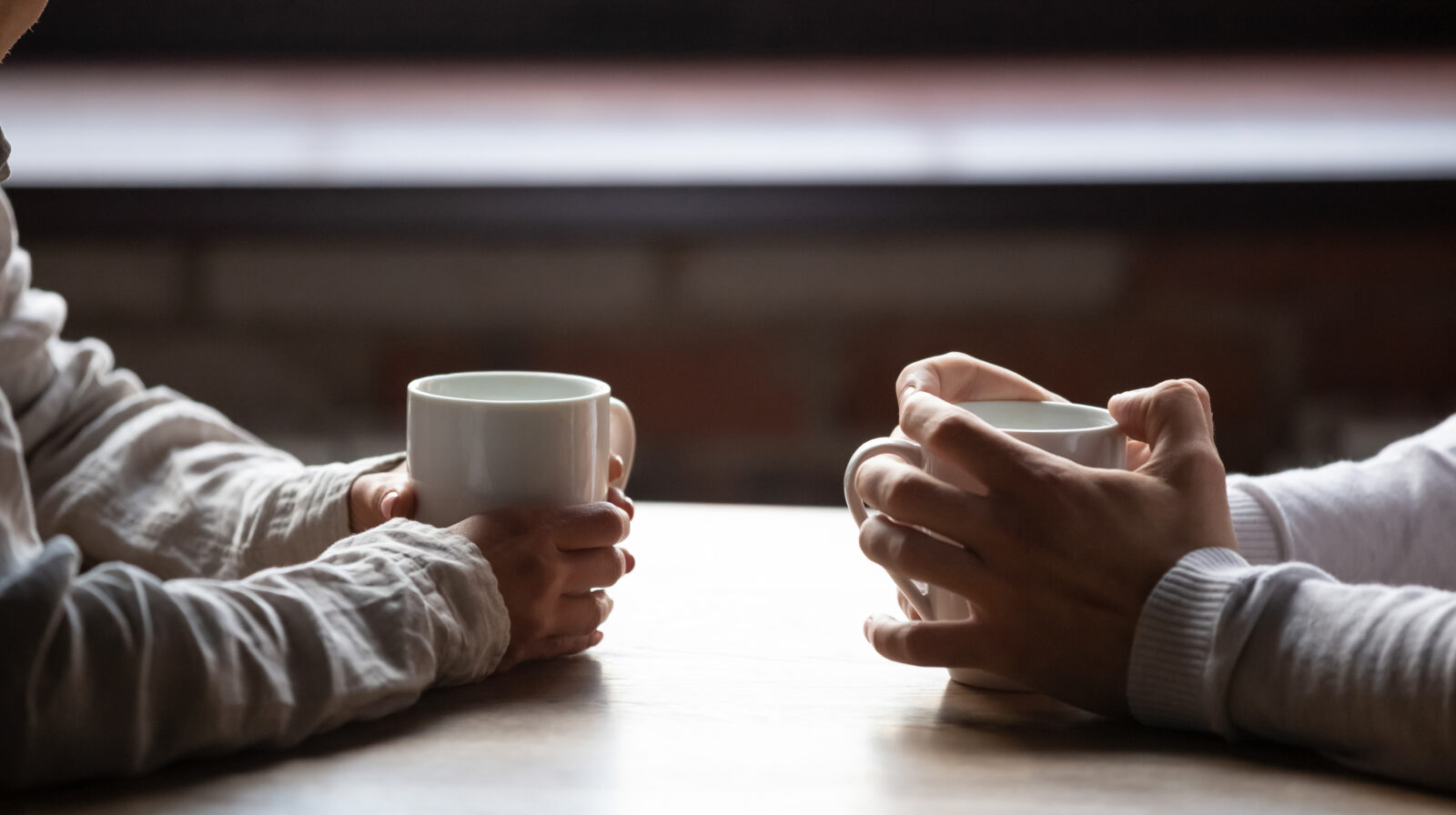 Close up of couples' hands holding coffee cups at Pegasus Coffee on Bainbridge Island.