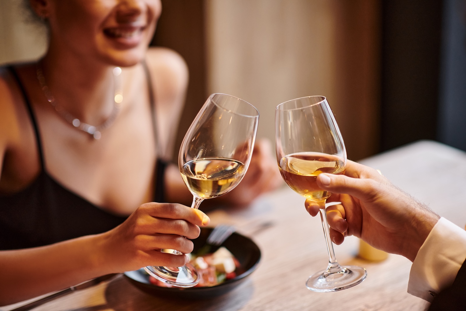 A woman at a table clinking wine glasses with a man at one of the most romantic restaurants in Durham, NC.