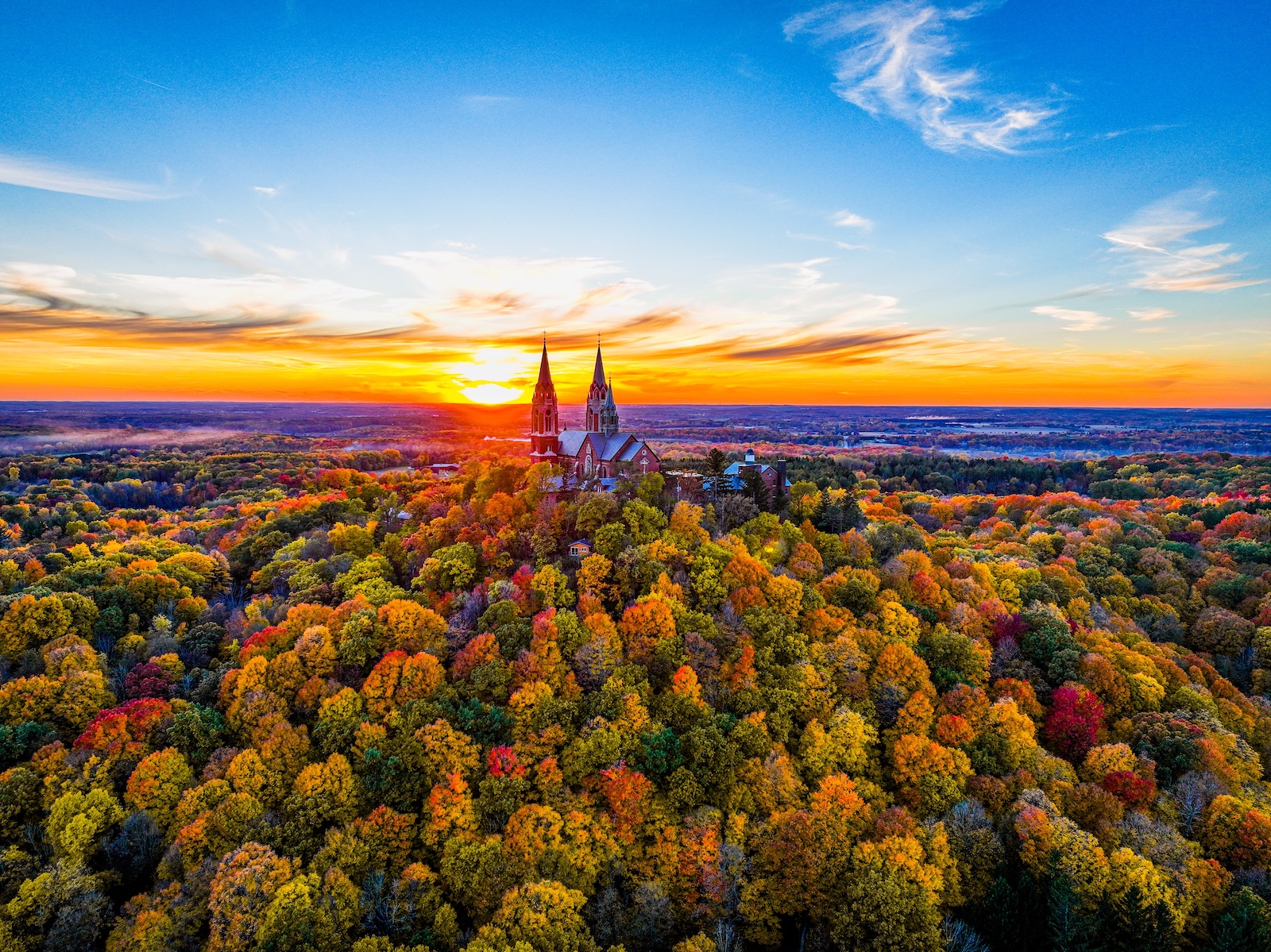 Holy Hill Basilica in the distance surrounded by fall foliage during sunrise, what you can see during one of the best fall getaways near Chicago.