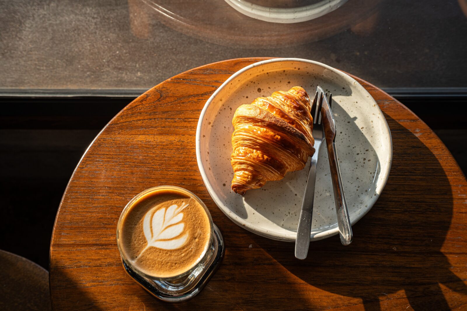 Latte and Croissant on wood table at coffee shops on Bainbridge Island.