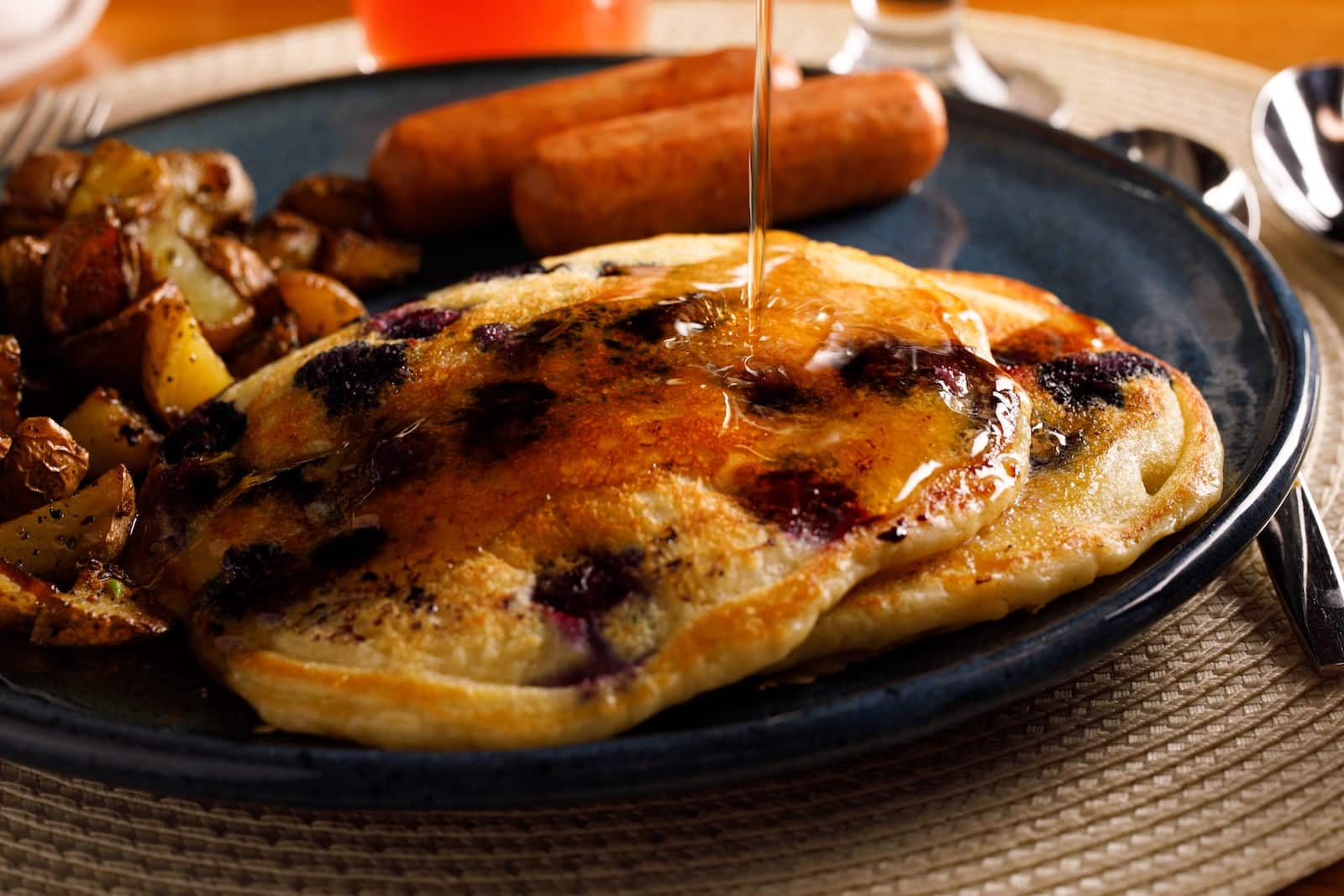 Blueberry pancakes with maple syrup and a side of sausage served at one of the best Wausau hotels.